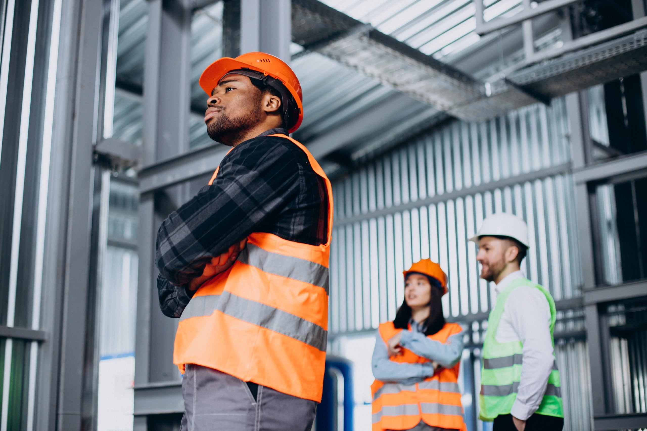 three factory workers safety hats discussing manufacture plan 1 1 1 scaled